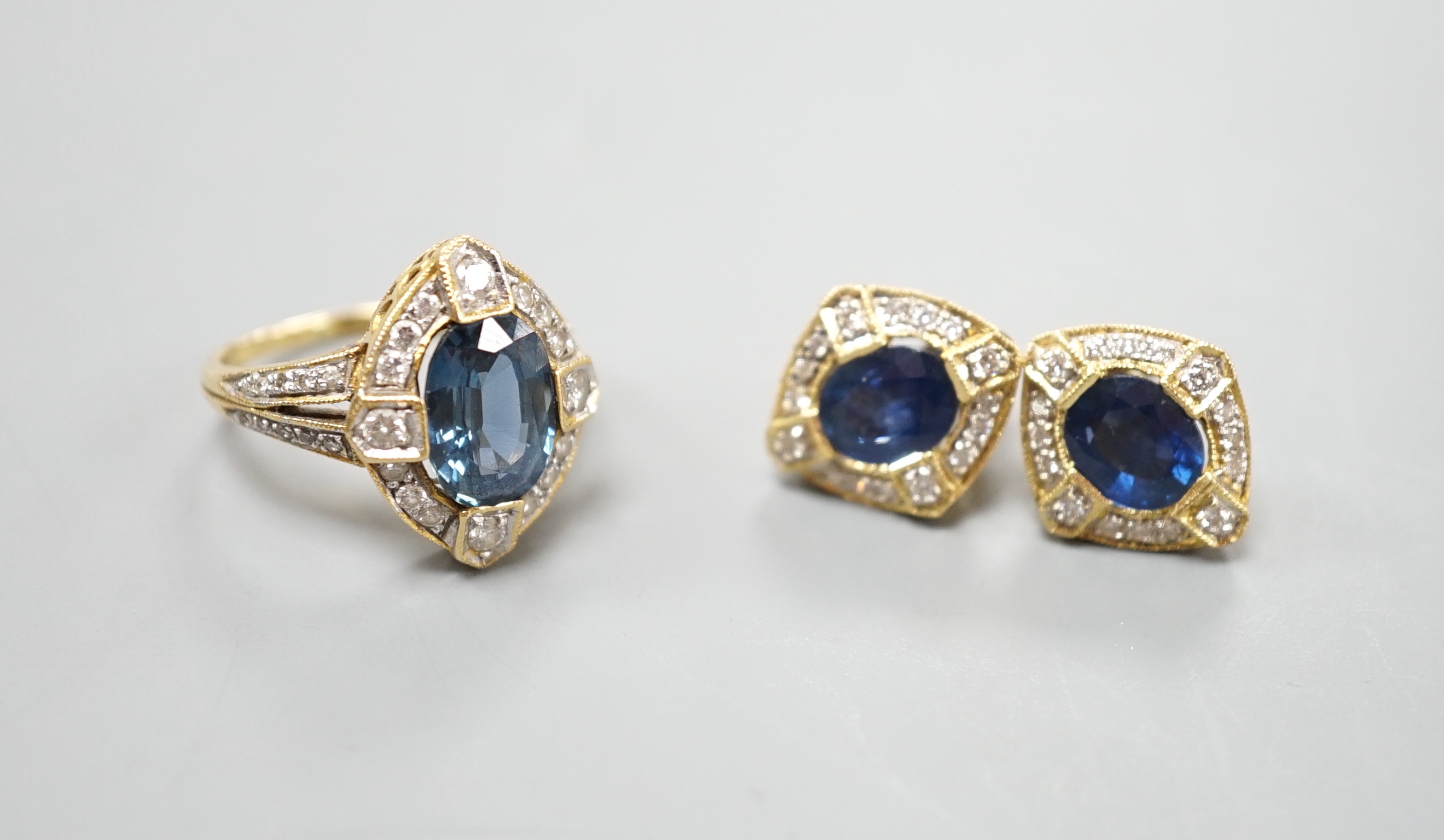 A modern suite of 18k, sapphire and diamond cluster set jewellery, comprising a dress ring, size L/M and pair of earrings, 14mm, gross weight 9.9 grams.